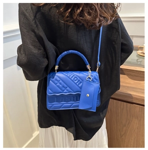 Detail of blue textured handbag with FASHION lettering and woven handle in macro view