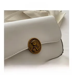 Dettaglio borsa in pelle bianca con fibbia metallica a rilievo con orso stile vintage