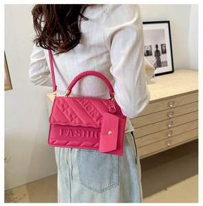 Detail of magenta quilted handbag with FASHION relief and woven handle on model