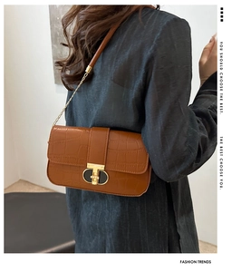 Detail of caramel brown croc-effect leather crossbody bag with golden geometric buckle