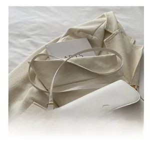 Dettaglio di una borsa a tracolla in pelle color crema con fibbia dorata vintage