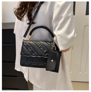 Detail of black quilted leather shoulder bag with embossed Fashion logo and braided handle