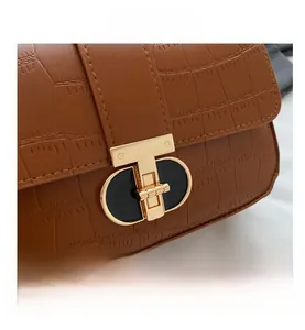 Close-up of brown crocodile texture leather bag with elegant gold T-shaped buckle detail