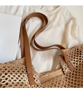 Détail de la bandoulière en cuir marron et de la texture en paille tressée du sac cabas