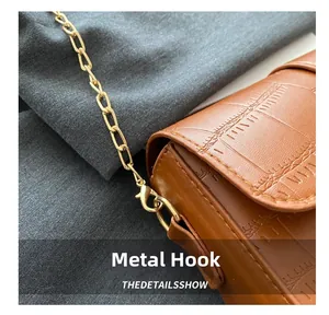 Close-up of golden hardware hook on brown crocodile pattern leather shoulder bag