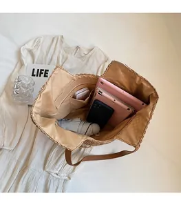 Détail de l'intérieur spacieux d'un sac cabas en paille avec compartiments et accessoires