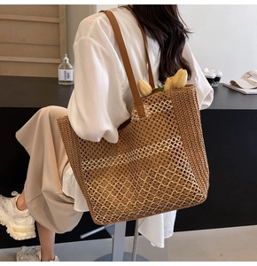 Détail de la texture tressée et des anses en similicuir d'un grand sac cabas en paille