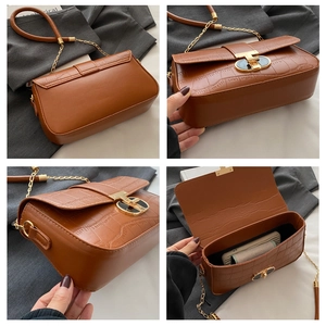 Detail view of brown crocodile embossed shoulder bag with gold chain strap and metal buckle