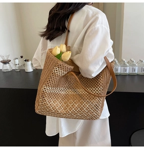 Gros plan détaillé du sac cabas en paille marron avec rayures blanches et anses en cuir