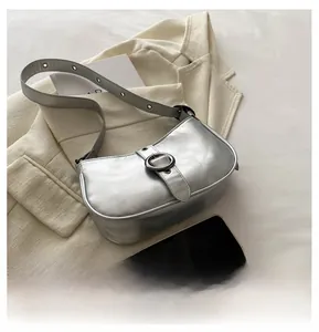 Dettaglio borsa a mezzaluna argento con tracolla regolabile su un blazer elegante