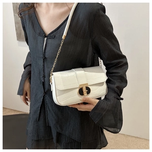 Close-up of white crocodile pattern bag featuring a black and gold metal twist lock