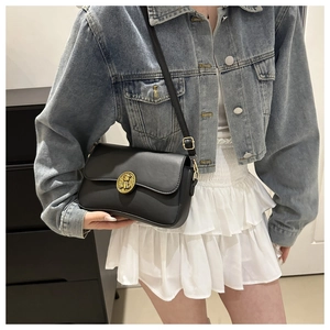 Dettaglio della borsa a tracolla nera con fibbia dorata su un outfit casual chic