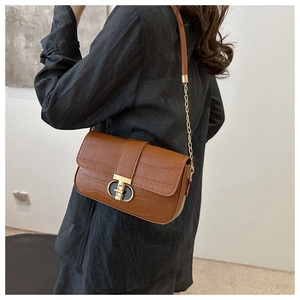 Detail of brown crocodile pattern shoulder bag with gold metal clasp and chain strap
