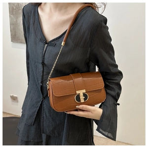 Detailed side view of brown croc-effect crossbody bag with gold T-bar metal buckle and chain