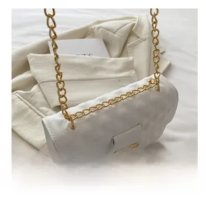 Nahaufnahme einer cremefarbenen Stepptasche mit goldener Kette und Metall-Drehverschluss
