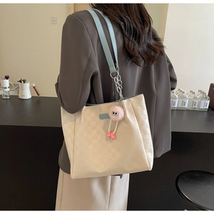 Lifestyle view of a plaid tote bag with blue straps and a cute pink plush charm pendant