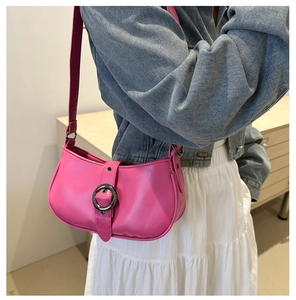 Dettaglio di una borsa a spalla in pelle rosa acceso con fibbia metallica sul modello