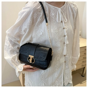 Close-up of black crocodile pattern shoulder bag with elegant gold metal buckle and chain strap