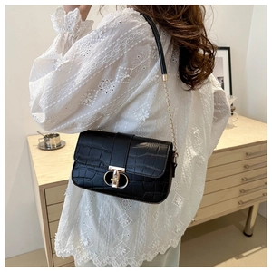 Elegant black crocodile embossed crossbody bag with gold hardware shown on shoulder