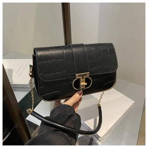 Detail of black crocodile-embossed leather handbag featuring a gold metallic clasp and chain