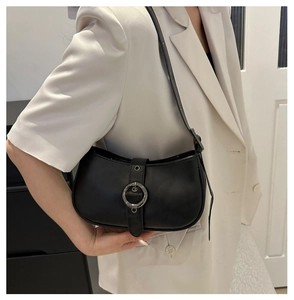 Dettaglio borsa sottobraccio nera a semicerchio con fibbia argento su blazer bianco