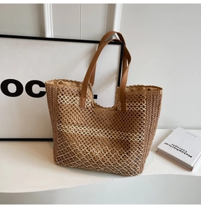Détail d'un sac cabas en paille tissée avec rayures blanches et anses en cuir marron