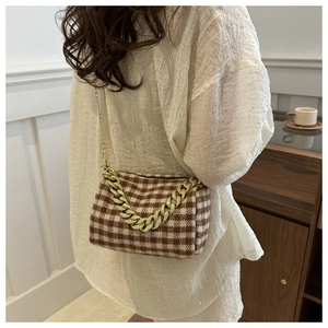 Détail du sac à carreaux marron avec une chaîne décorative dorée élégante