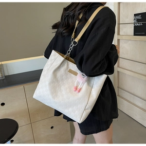 Close-up of checkered tote bag with fashion tag, plush charm and yellow strap detail