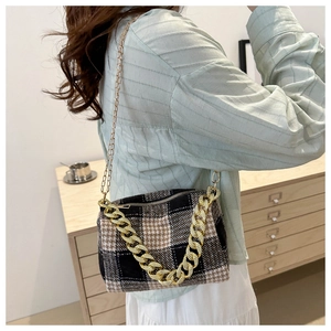 Détail d'un sac vintage à motif pied-de-poule avec grosse chaîne dorée décorative