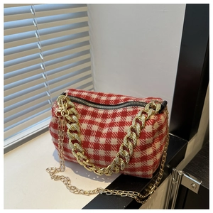 Détail du sac polochon à carreaux rouge et blanc avec chaîne dorée et finitions en métal