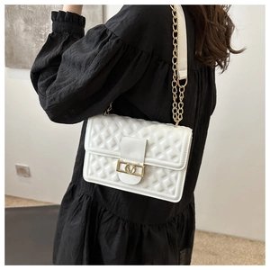 Detail der weißen Stepptasche mit goldenem V-Verschluss und Leder-Kettengurt am Modell