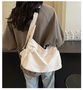 Detail of beige nylon crossbody bag featuring stylish metal zippers and wide strap
