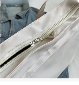 Close-up of smooth silver metal zipper with a unique white triangular puller on tote bag