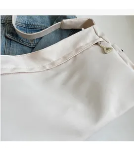 Close-up of the beige nylon fabric texture and smooth zipper detail on the shoulder bag