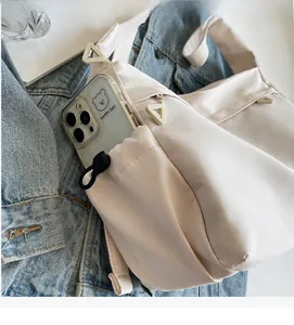 Detail of water-resistant cream nylon bag side pocket showing smartphone storage space
