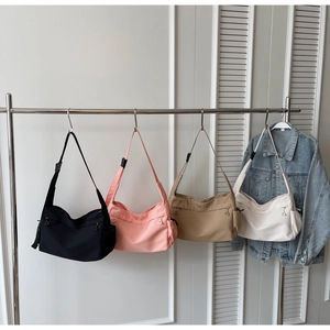 Large capacity nylon shoulder bags in four colors hanging on a modern display rack