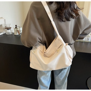 Detail of oat-colored nylon tote bag featuring side drawstrings and wide fabric strap