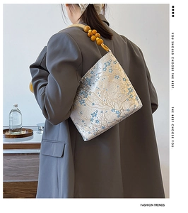Detail of floral embroidery on silk texture shoulder bag with wooden bead handle