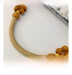 Detail of silk bucket bag handle featuring natural wooden beads and woven beige cord