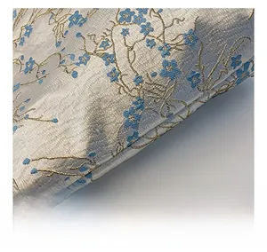 Detail of silk brocade fabric with golden plum blossom patterns and rich texture