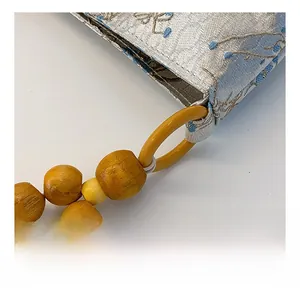 Detailed close-up of light blue silk embroidery fabric and natural wooden bead handle