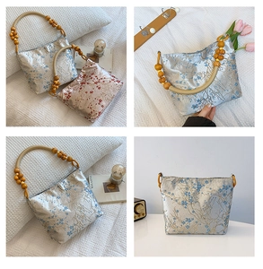 Detailed macro view of silk-textured bucket bag featuring plum blossoms and wooden bead handle