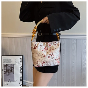 Detailed texture of silk brocade fabric with plum blossom patterns and wooden bead handle
