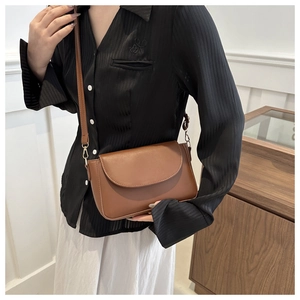 Close-up of a brown crossbody bag with a matte texture on a female model
