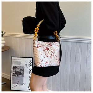 Detail of vintage wooden bead handle and red plum blossom print on silk bucket bag