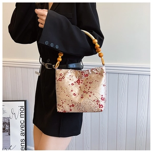 Detailed embroidery on champagne gold silk handbag with handcrafted wood bead strap