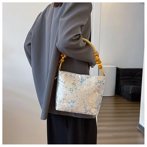 Detail of silk texture bucket bag with wooden beads and blue floral pattern for women