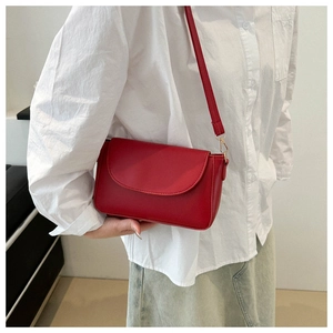 Detail of red minimalist flap square bag with gold hardware and slim shoulder strap