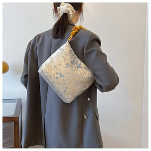 Close-up of silk-textured jacquard fabric and wooden bead strap on a bucket bag