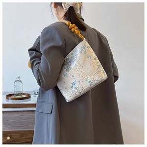 Detail view of floral jacquard fabric and wooden bead strap on vintage shoulder bag